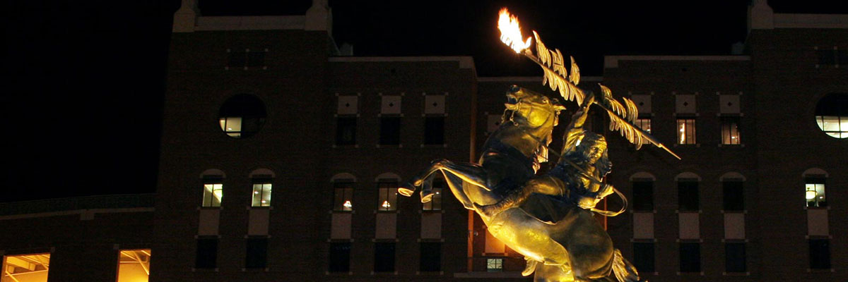 Doak stadium at night with the unconquered statue in foreground
